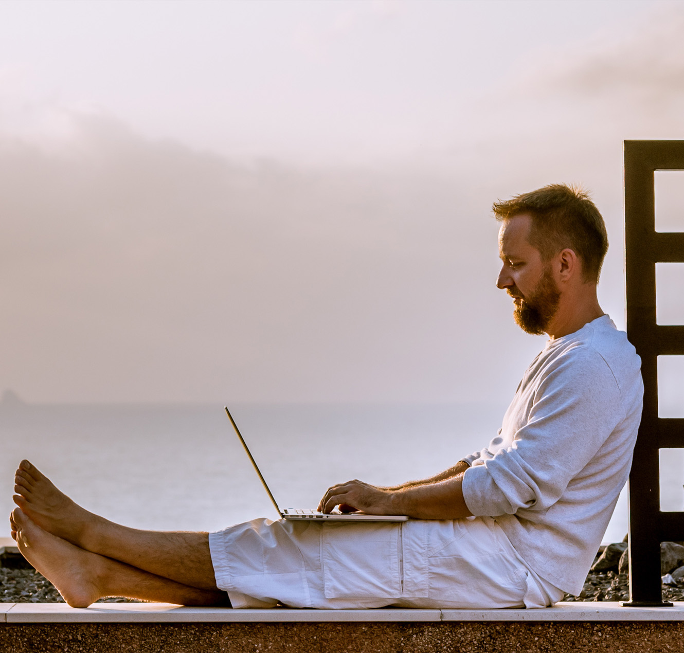man working on laptop near beach