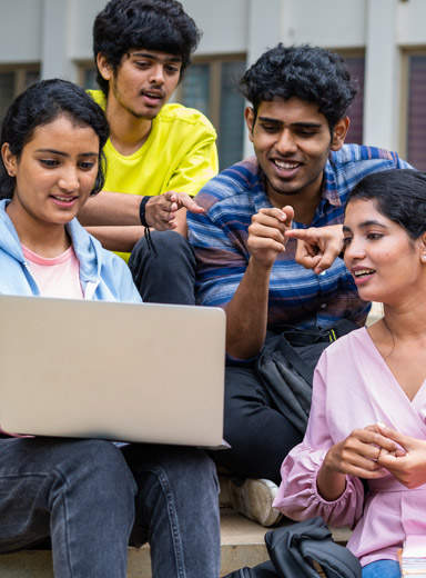 Indian College Students Posing with a Thumbs Up in Campus Hallway with Books in Hand